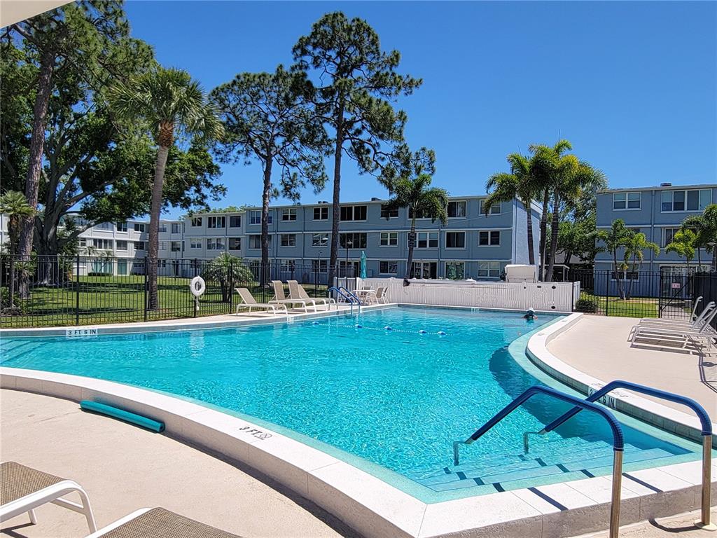 A swimming pool with lounge chairs sits in front of a multi-story apartment building — 4715 BAY STREET NE UNIT 225, ST PETERSBURG, FL