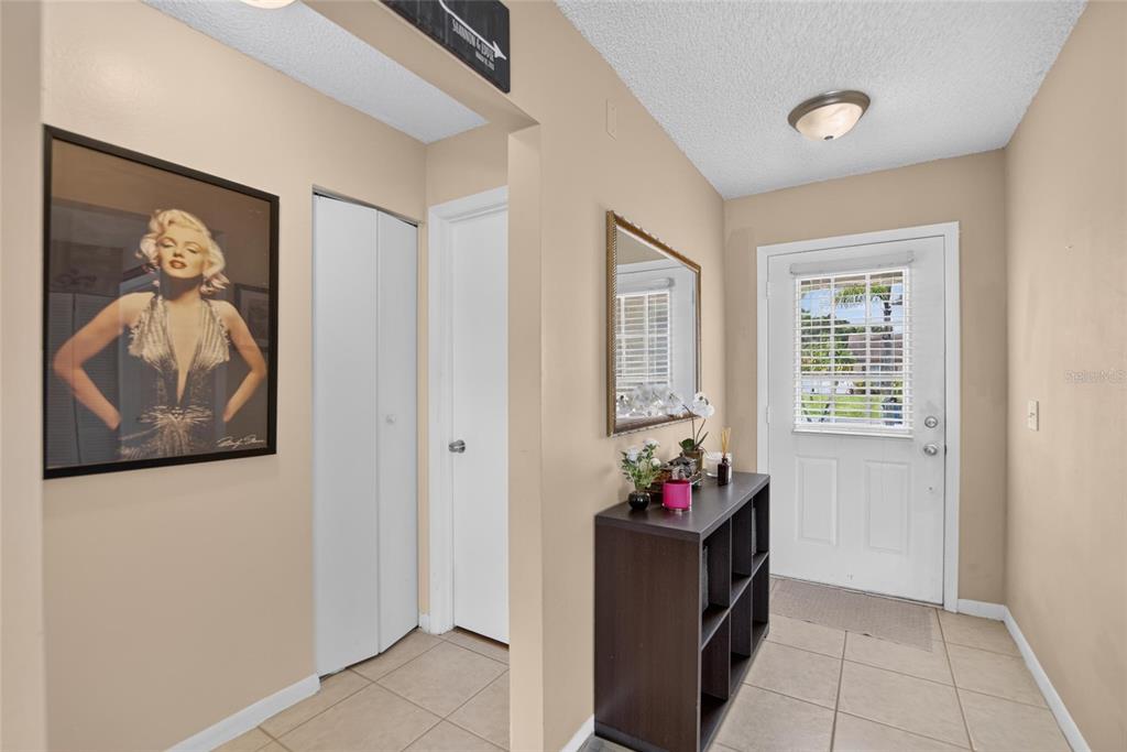 An entryway features beige walls, tile flooring, a Marilyn Monroe print, and a white door — 9063 DIXIANA VILLA CIRCLE, TAMPA, FL