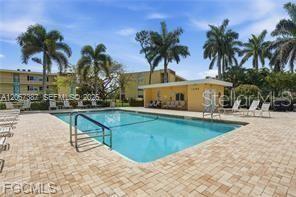 A multi-story apartment building exterior features yellow walls, black railings, and a landscaped lawn — 1085 FOREST LAKES DRIVE UNIT 102, NAPLES, FL