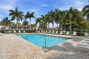 A rectangular swimming pool is surrounded by a paved deck, lounge chairs, and palm trees — 1085 FOREST LAKES DRIVE UNIT 102, NAPLES, FL