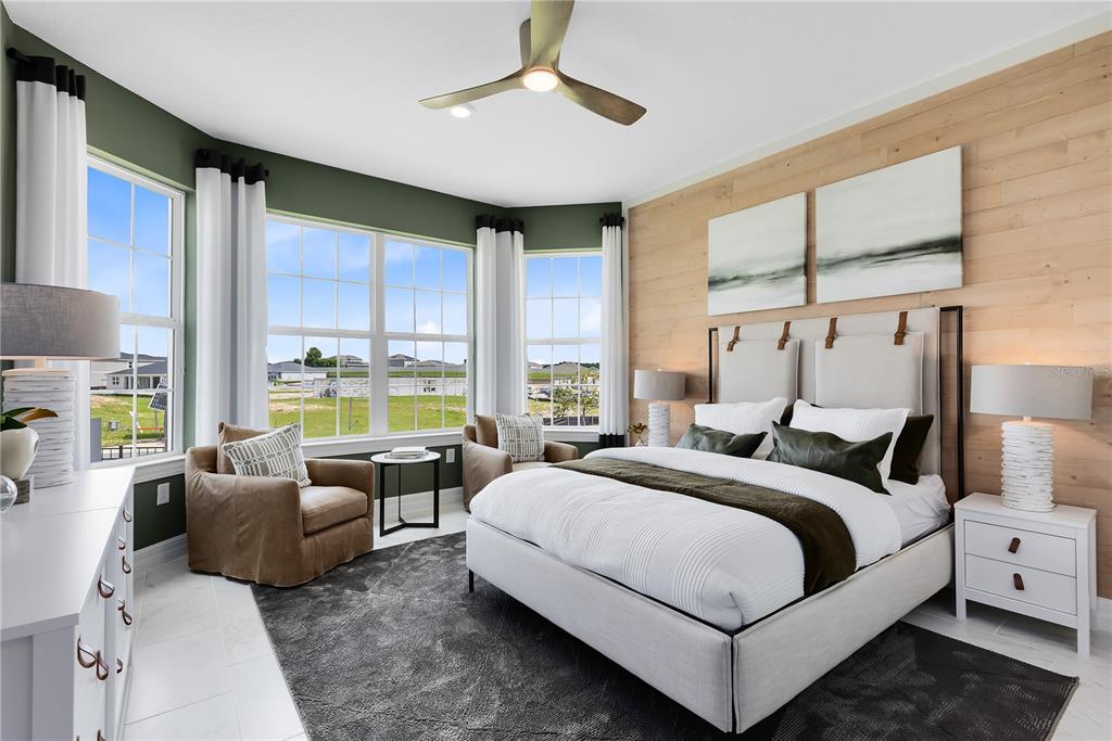 A bedroom features a wood-paneled accent wall, a bay window, and a modern ceiling fan — 5243 HANDSOME HILLS DRIVE, MOUNT DORA, FL