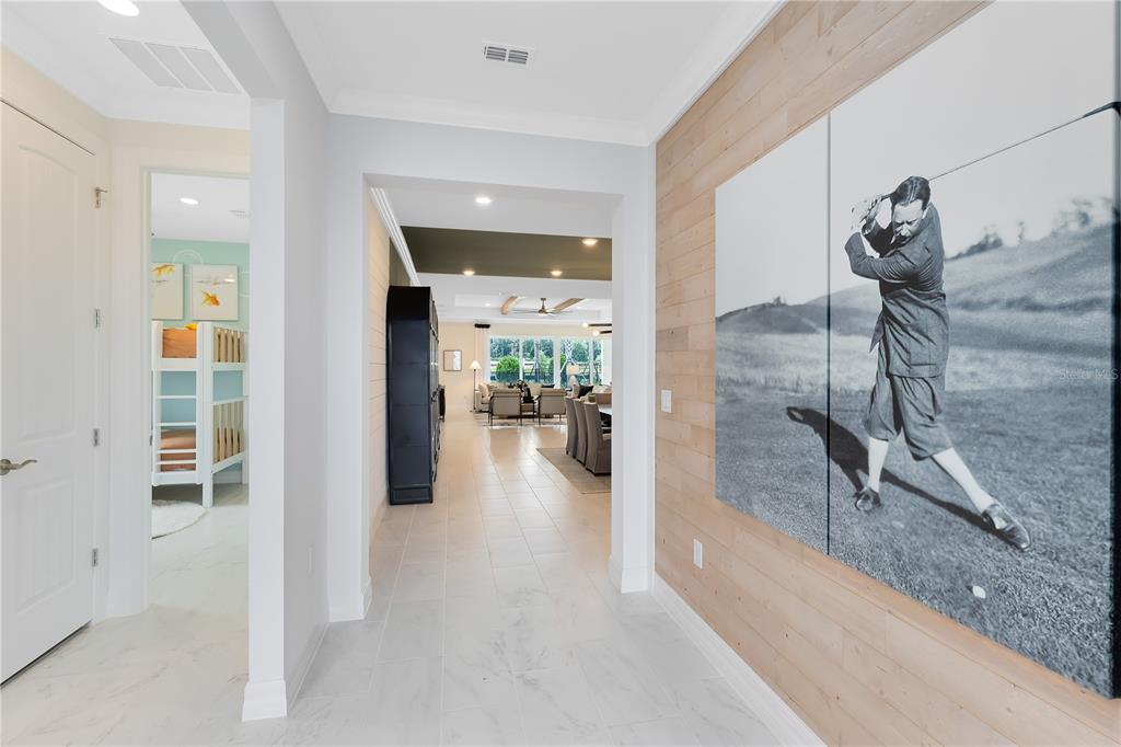 A hallway with light tile floors leads to an open living area featuring wood-paneled walls — 5243 HANDSOME HILLS DRIVE, MOUNT DORA, FL