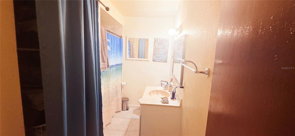 A bathroom features a vanity with a sink, a shower with a curtain, and tile flooring — 1135 HOLDEN AVENUE UNIT 1/2, ORLANDO, FL