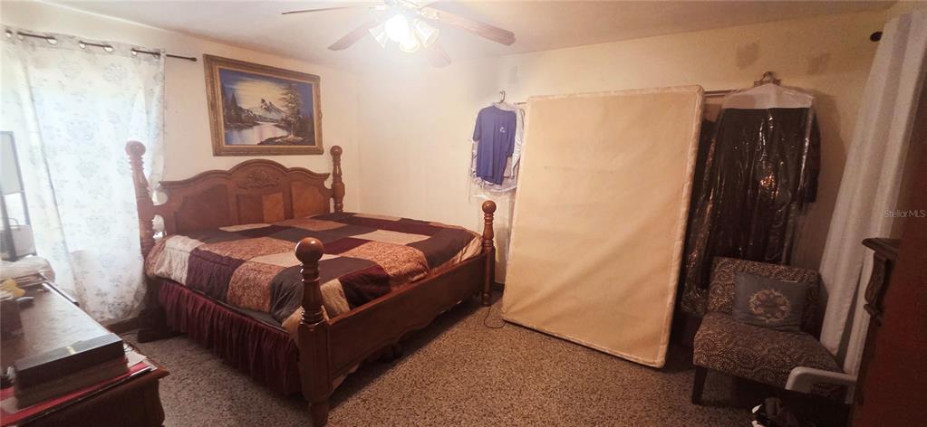 A bedroom features a wooden bed frame, a mattress leaning against the wall, and carpeted flooring — 1135 HOLDEN AVENUE UNIT 1/2, ORLANDO, FL