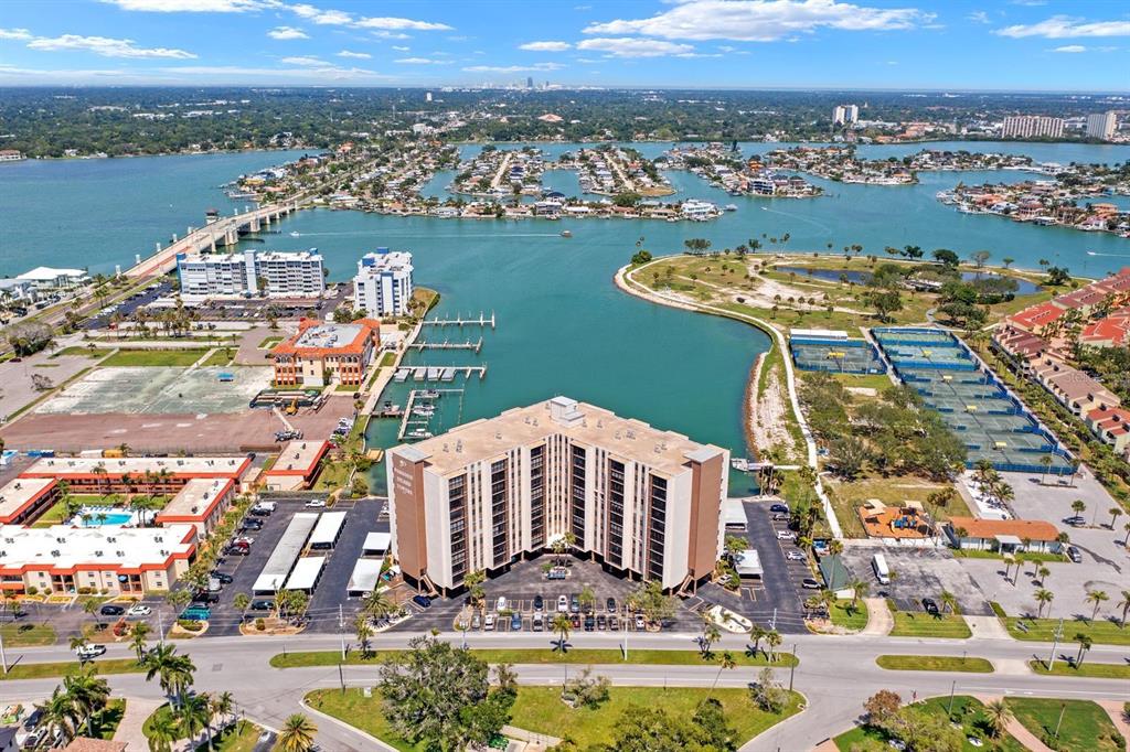 An aerial view shows a multi-story apartment building near a bay with a bridge — 10355 PARADISE BOULEVARD UNIT 512, TREASURE ISLAND, FL