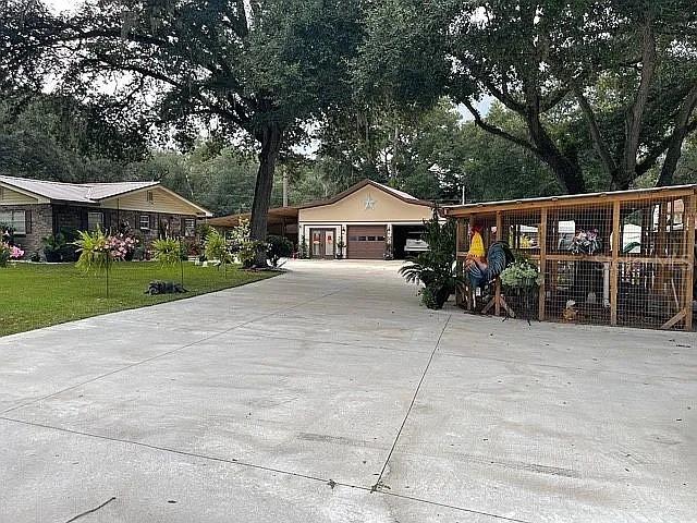 A large concrete driveway leads to a detached garage and a fenced outdoor animal enclosure — 9068 131ST LOOP, LIVE OAK, FL