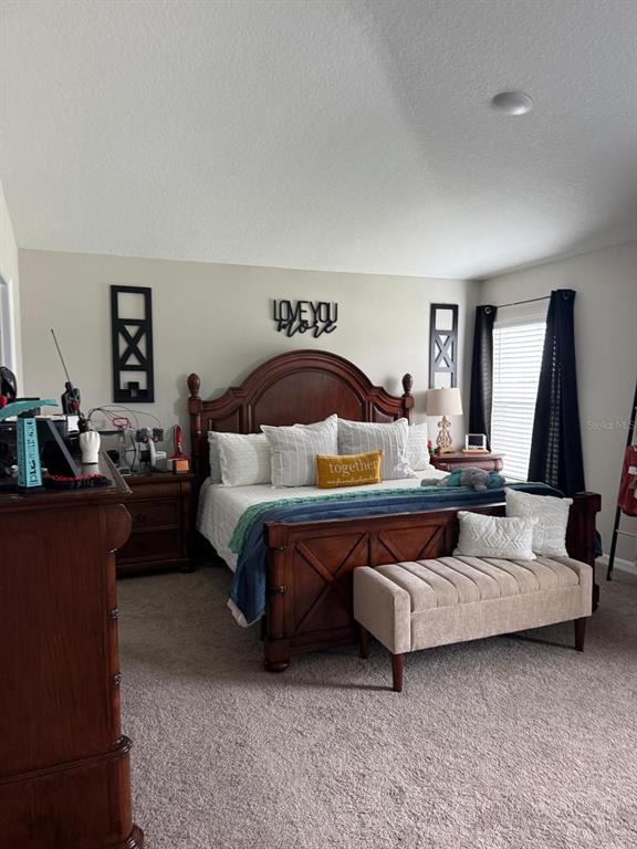 A bedroom features a wooden bed frame, a beige bench, and dark curtains — 5508 MADDIE DRIVE, HAINES CITY, FL