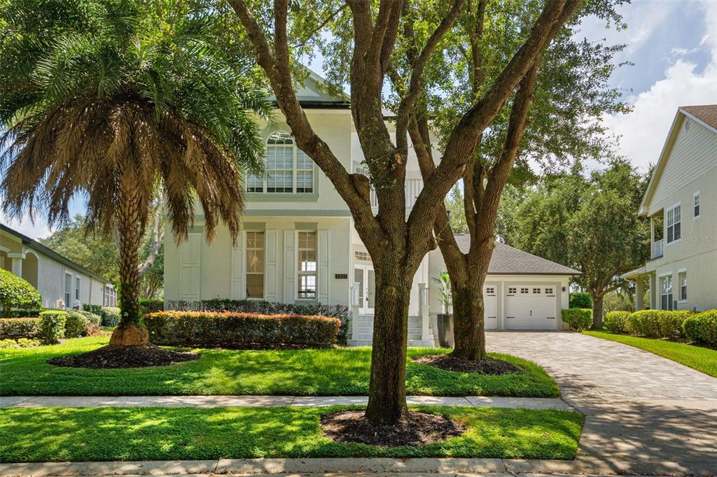 A two-story house with a paved driveway, a palm tree, and large oak trees — 5927 CAYMUS LOOP, WINDERMERE, FL