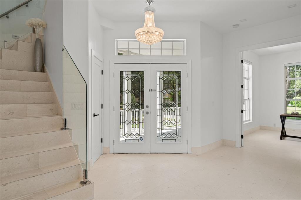 A bright foyer features a crystal chandelier, a glass-railed staircase, and double front doors — 5927 CAYMUS LOOP, WINDERMERE, FL