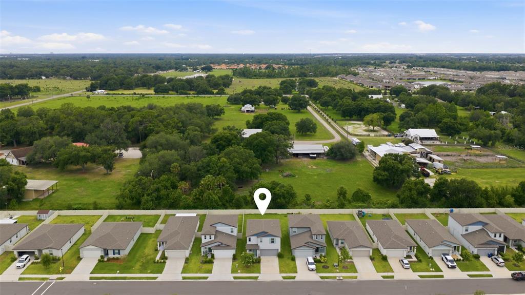 An aerial view shows a row of suburban houses bordering a large, open green field — 7117 BOGGY CREEK PLACE, PARRISH, FL