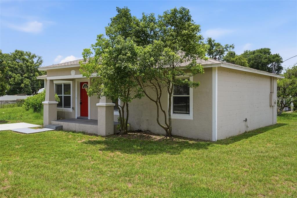 A single-story tan house with a red front door and a covered porch — 5331 5TH STREET, ZEPHYRHILLS, FL