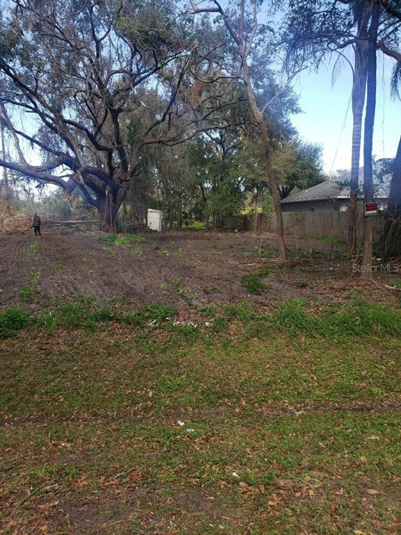 A cleared, dirt-covered vacant lot features large mature trees and a wooden fence — 4217 W JACKSON STREET, ORLANDO, FL