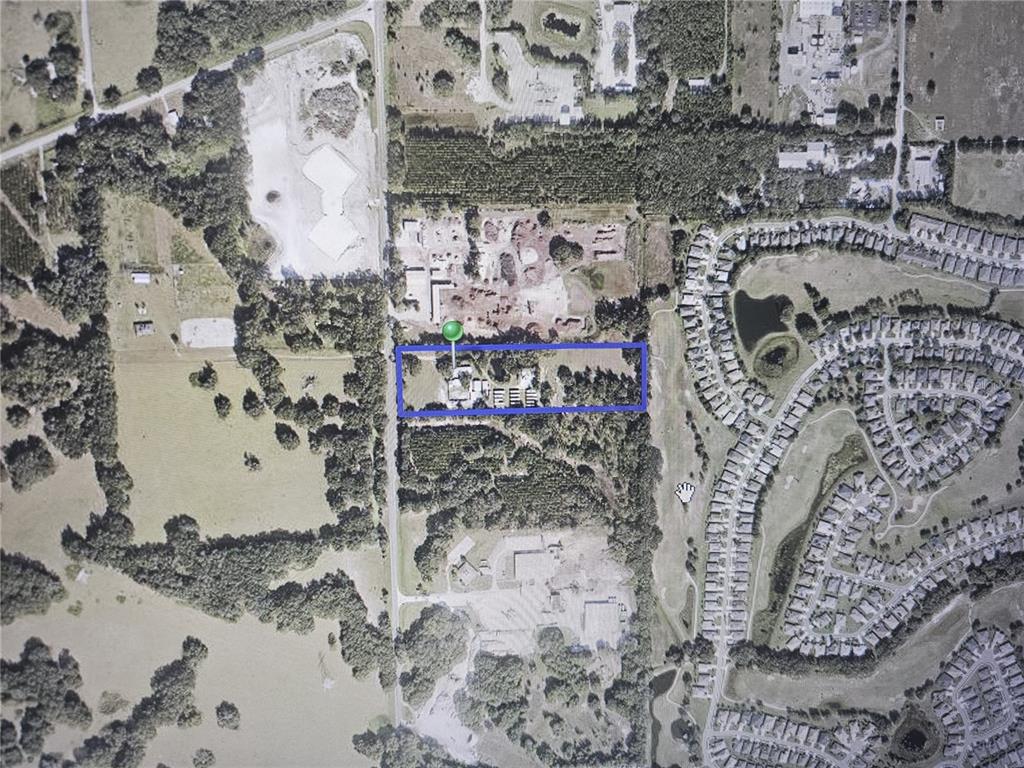 This aerial map shows a rectangular property outlined in blue surrounded by trees and development — 26630 COUNTY ROAD 33, OKAHUMPKA, FL