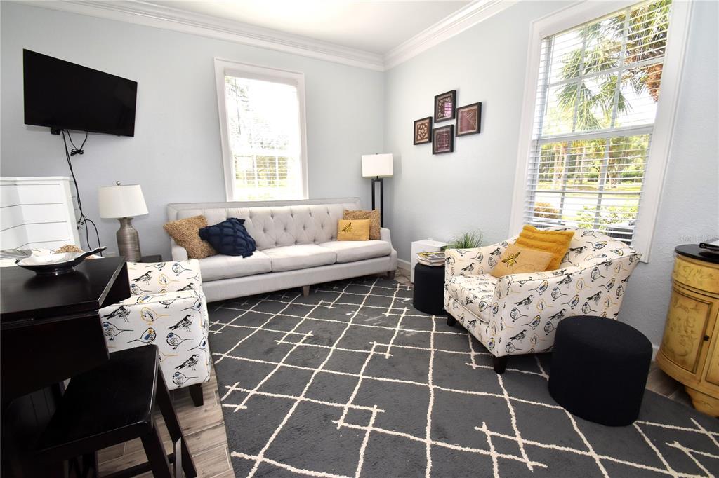 A living room features a gray tufted sofa, patterned armchairs, and a geometric area rug — 51 MAC EWEN DRIVE UNIT 1, OSPREY, FL