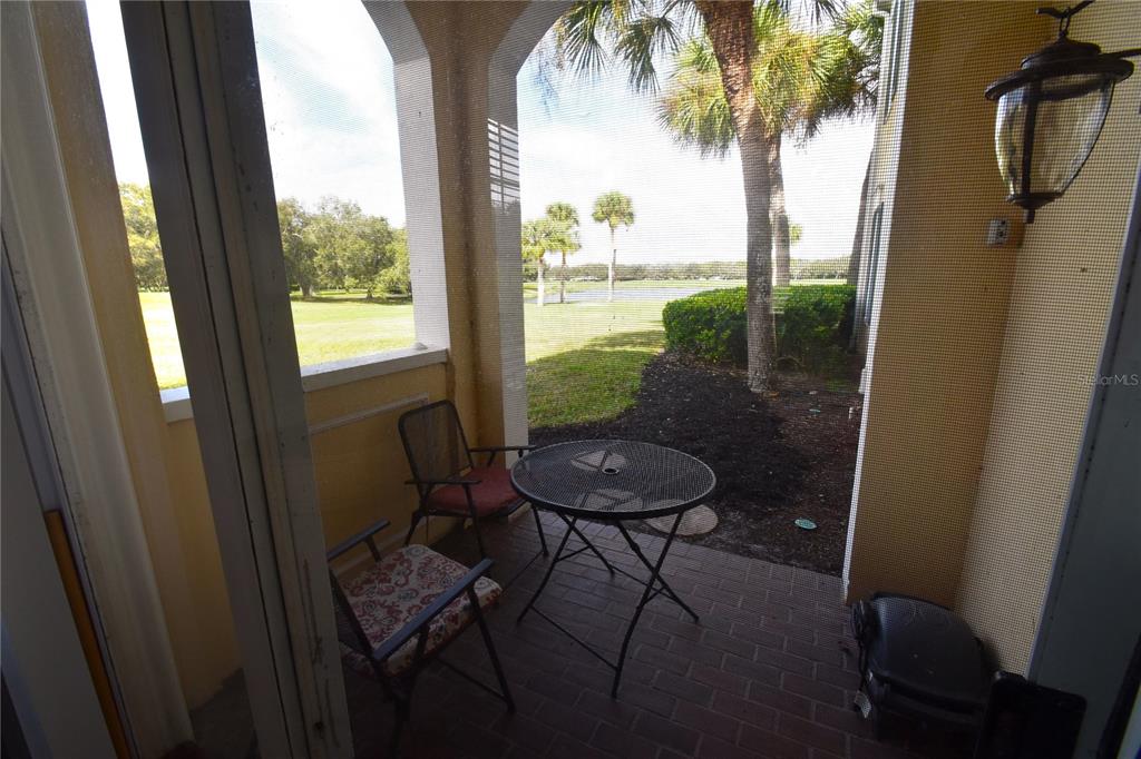 A screened-in patio features a small metal table and chairs overlooking a grassy golf course — 51 MAC EWEN DRIVE UNIT 1, OSPREY, FL