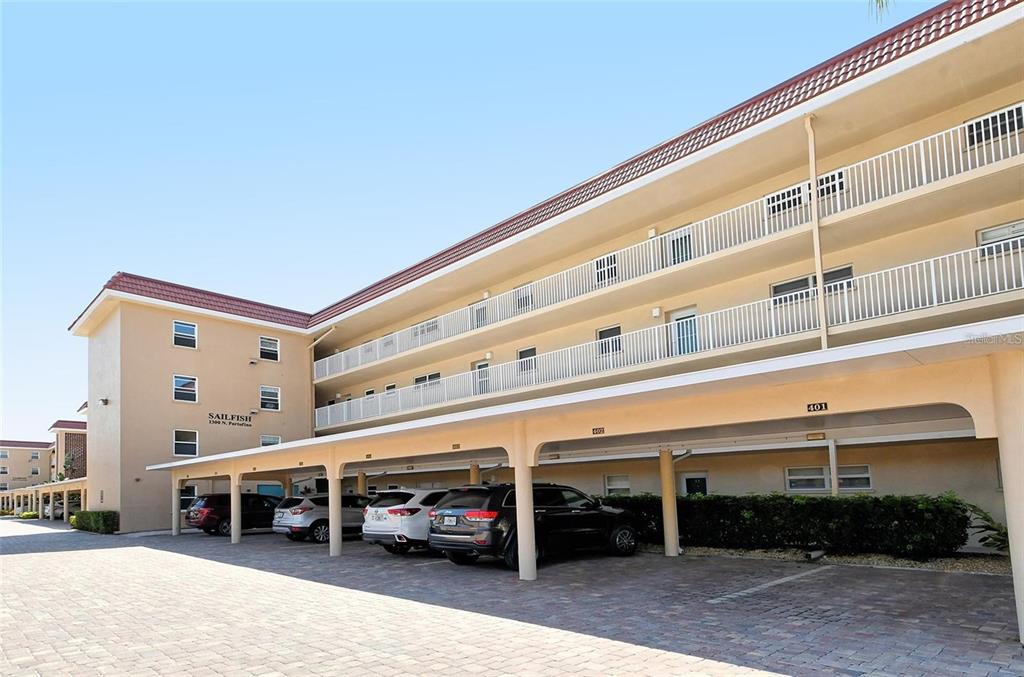 A multi-story apartment building with a covered parking area and a paved driveway — 1300 N PORTOFINO DRIVE UNIT 305, SARASOTA, FL