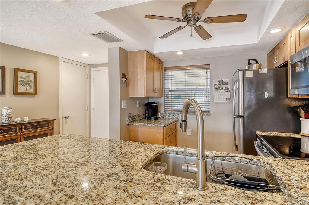 A kitchen features granite countertops, light wood cabinets, a stainless steel refrigerator, and a sink — 1300 N PORTOFINO DRIVE UNIT 305, SARASOTA, FL