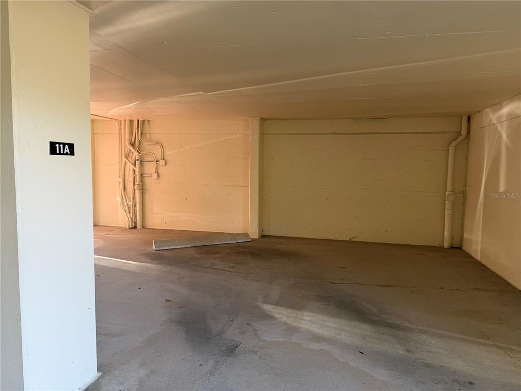 A covered parking space with a concrete floor and a numbered pillar — 50 COE ROAD UNIT 322, BELLEAIR, FL