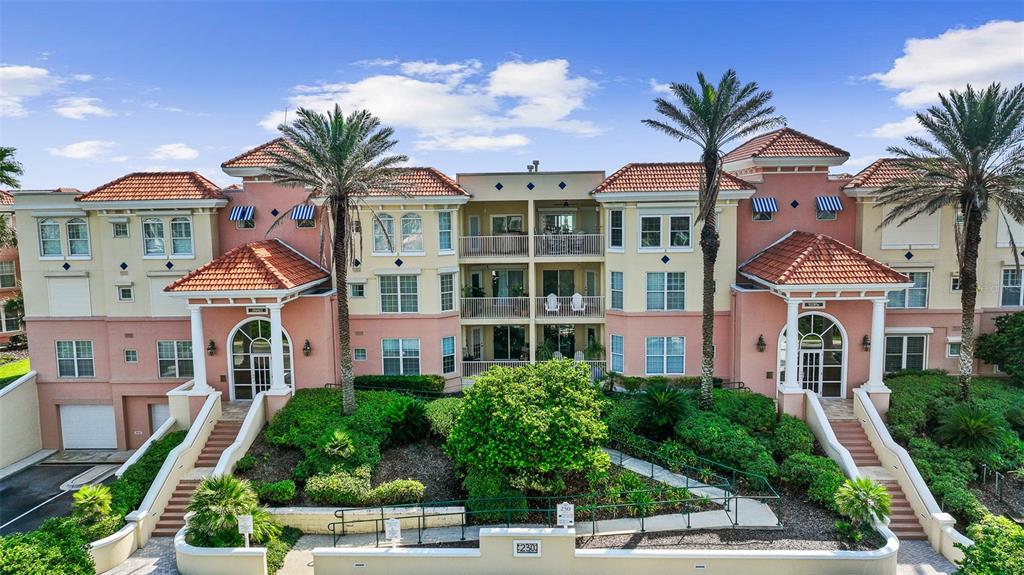 A multi-story peach-colored apartment building features tiled roofs, arched entryways, and palm trees — 230 N SERENATA DRIVE UNIT 711, PONTE VEDRA BEACH, FL