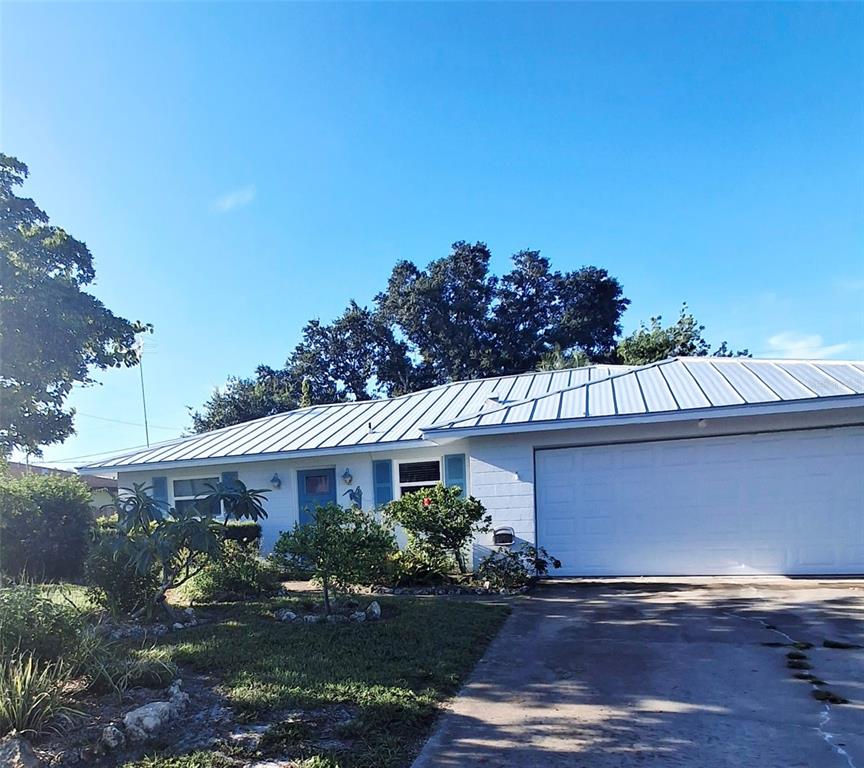 A single-story house with a white exterior, metal roof, and a two-car garage — 135 ENGLEWOOD HEIGHTS ROAD, ENGLEWOOD, FL