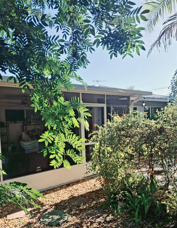 A screened-in patio overlooks a gravel yard with lush greenery and a large tree — 135 ENGLEWOOD HEIGHTS ROAD, ENGLEWOOD, FL