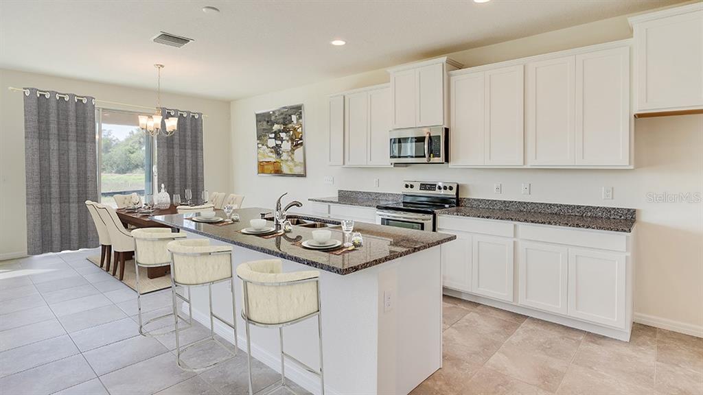 A kitchen features white cabinets, granite countertops, a center island, and an adjacent dining area — 35616 LOWERY TRAIL, ZEPHYRHILLS, FL