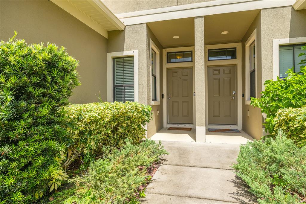 The exterior view shows a concrete walkway leading to two adjacent tan front doors — 13204 SAN BLAS LOOP, LARGO, FL
