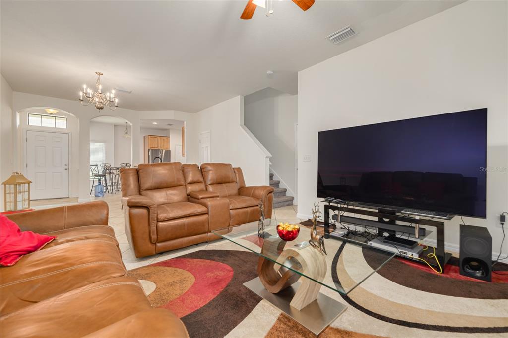 A living room features brown leather sofas, a glass coffee table, and a large television — 13204 SAN BLAS LOOP, LARGO, FL