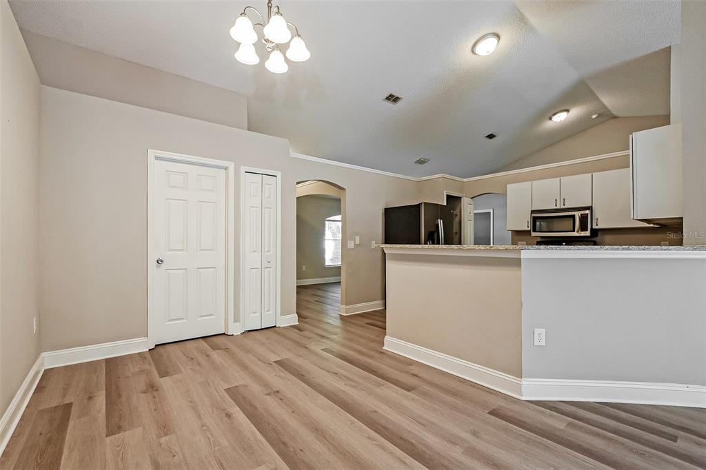 An open-concept living area features light wood-look flooring, a kitchen island, and vaulted ceilings — 2823 ARBOUR TRAIL COURT, DELTONA, FL