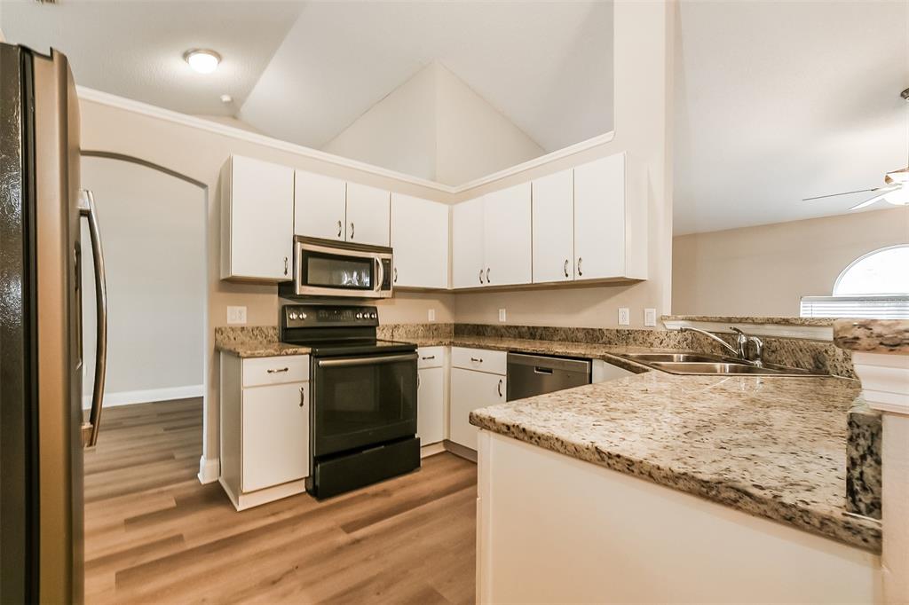 A kitchen with white cabinets, granite countertops, stainless steel appliances, and wood-look flooring — 2823 ARBOUR TRAIL COURT, DELTONA, FL