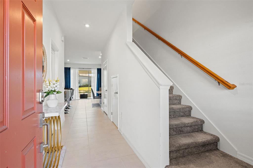 An entryway features a red door, tiled flooring, a staircase with carpet, and a hallway — 5725 HAVEN TERRACE, NOKOMIS, FL