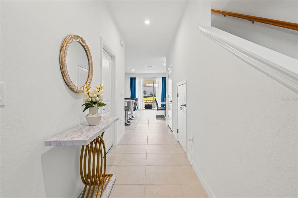 A hallway with tile flooring leads toward a bright living area with blue curtains — 5725 HAVEN TERRACE, NOKOMIS, FL