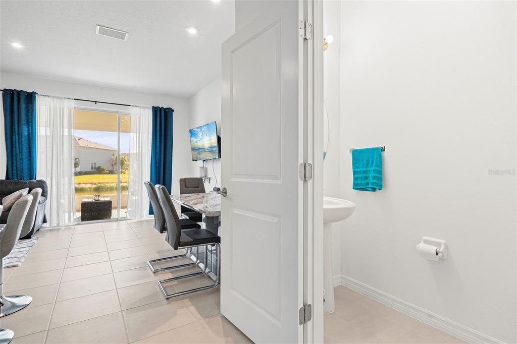 A view from a half bathroom looking out into a dining area with sliding doors — 5725 HAVEN TERRACE, NOKOMIS, FL
