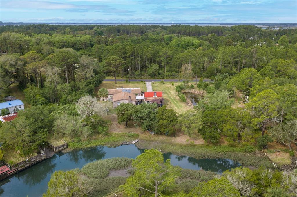An aerial view shows a house with a red roof situated near a waterfront — 16229 SHELLCRACKER ROAD, JACKSONVILLE, FL