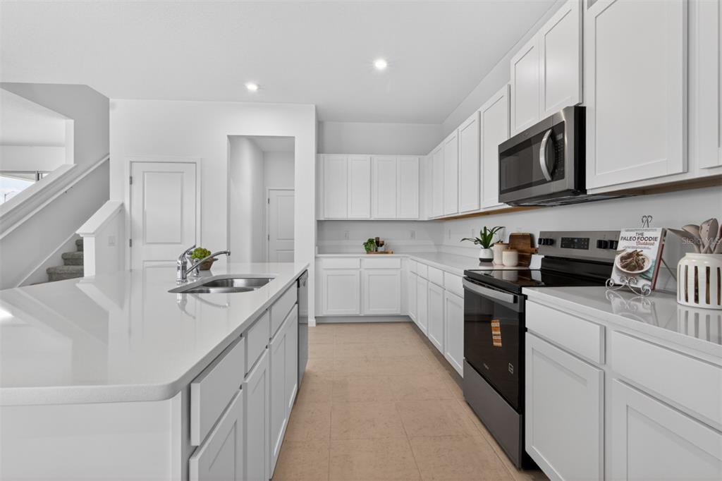 A modern kitchen features white cabinets, quartz countertops, stainless steel appliances, and a central island — 13636 SEAGRASS AVENUE, ORLANDO, FL