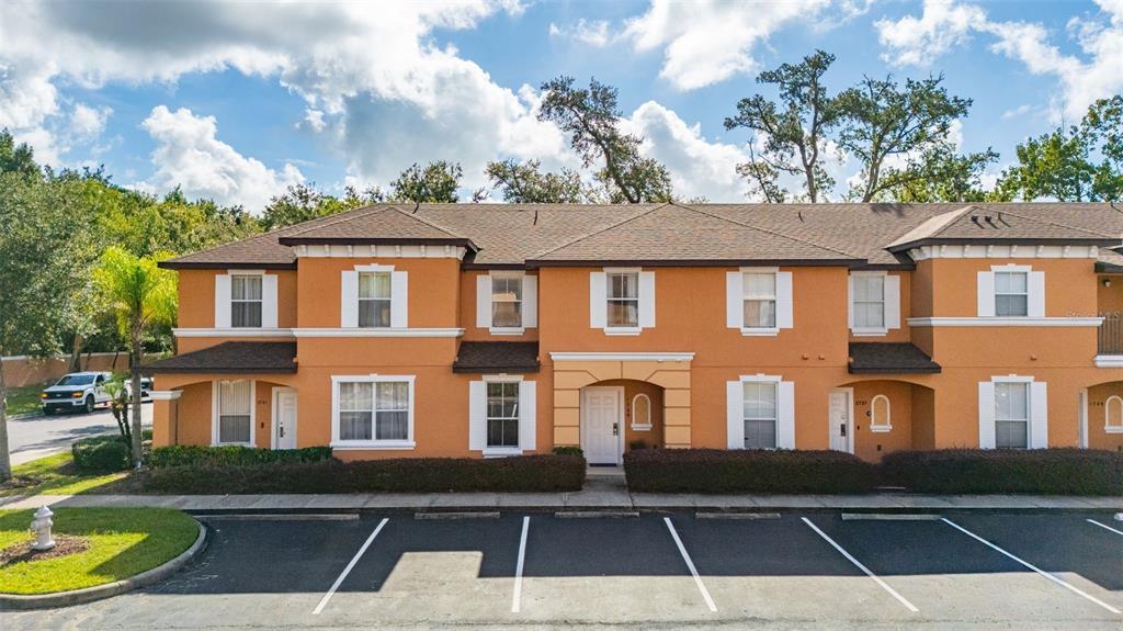 An exterior view of a two-story orange townhouse complex with a parking lot in front — 2739 COUPE STREET, KISSIMMEE, FL
