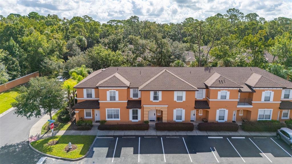 An aerial view of a two-story orange townhome complex with a parking lot in front — 2739 COUPE STREET, KISSIMMEE, FL