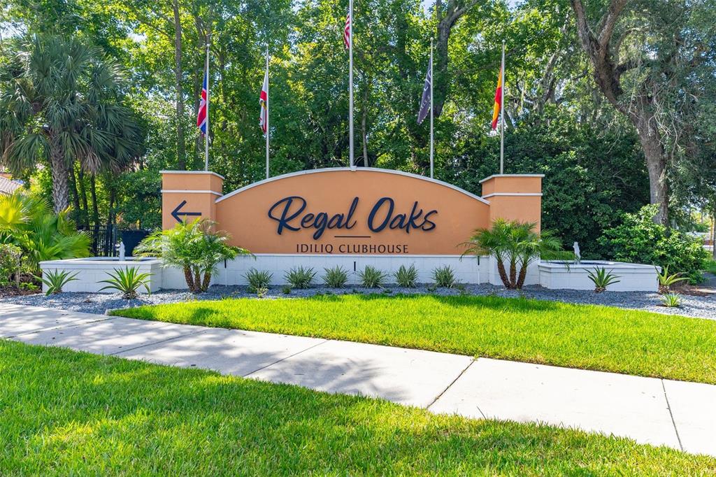 A sign for Regal Oaks Idiliq Clubhouse stands in front of trees and a sidewalk — 2739 COUPE STREET, KISSIMMEE, FL