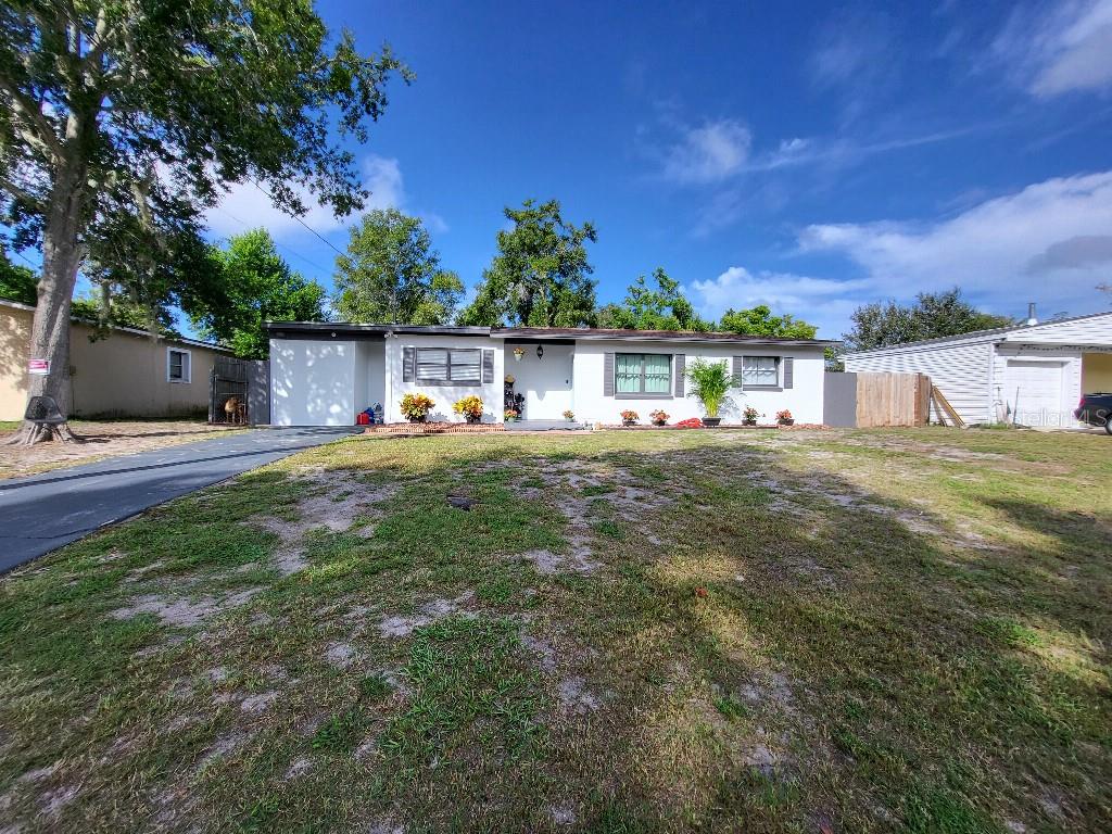 A single-story white house with a flat roof, a driveway, and a grassy front yard — 995 EMERALD DRIVE, MOUNT DORA, FL
