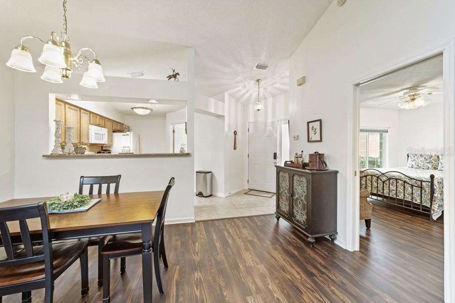 A dining area with wood-look flooring opens to a kitchen, entryway, and a bedroom — 2038 NW 50TH AVENUE, OCALA, FL