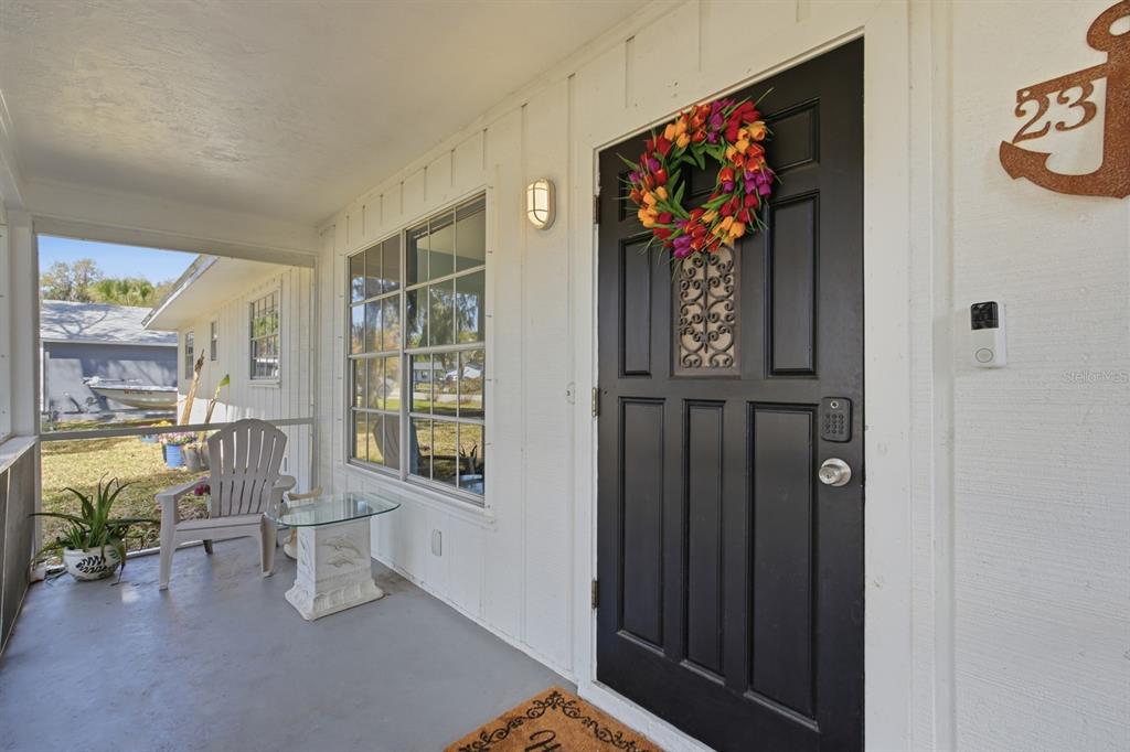 A covered porch features a black front door with a wreath and a white chair — 2329 LIME TREE, EDGEWATER, FL