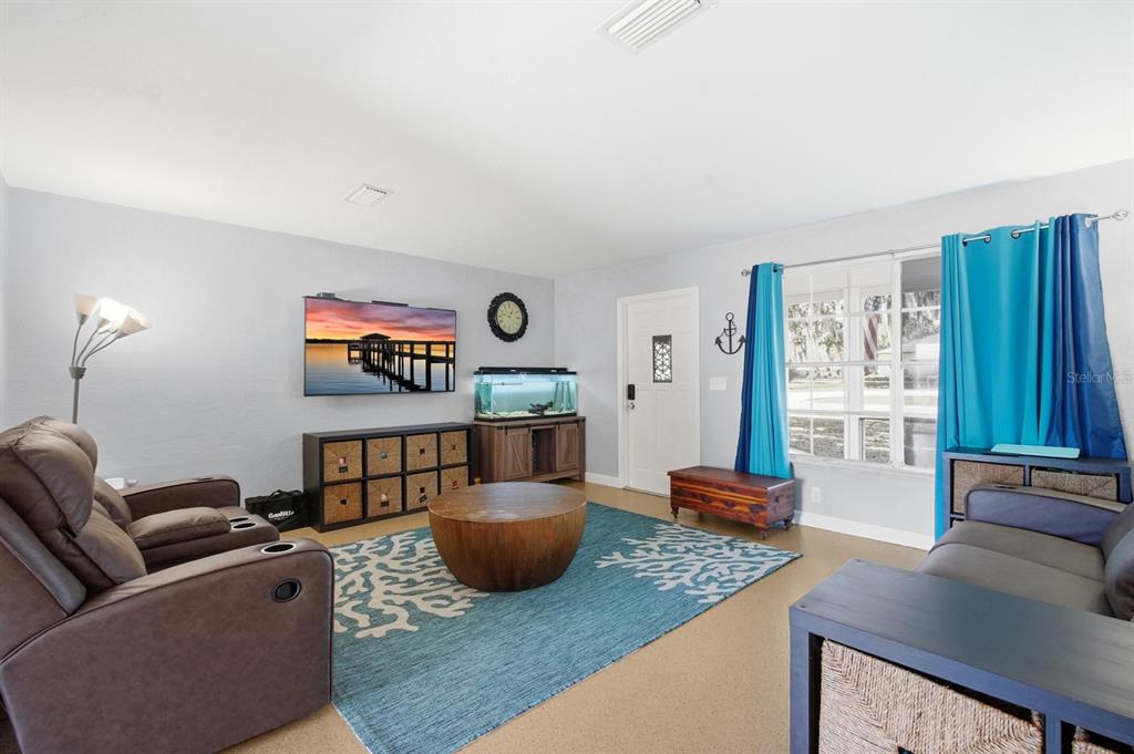 A living room features a brown recliner, a blue area rug, and a wall-mounted television — 2329 LIME TREE, EDGEWATER, FL