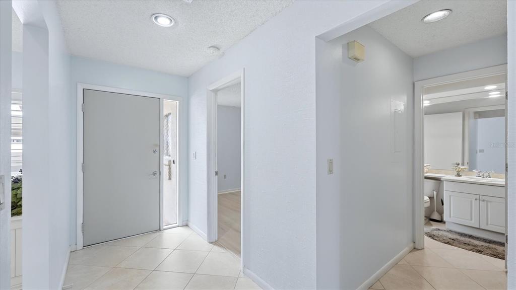 An entryway with light-colored tile flooring, a gray front door, and a nearby bathroom — 5350 MYRTLE UNIT 48, SARASOTA, FL