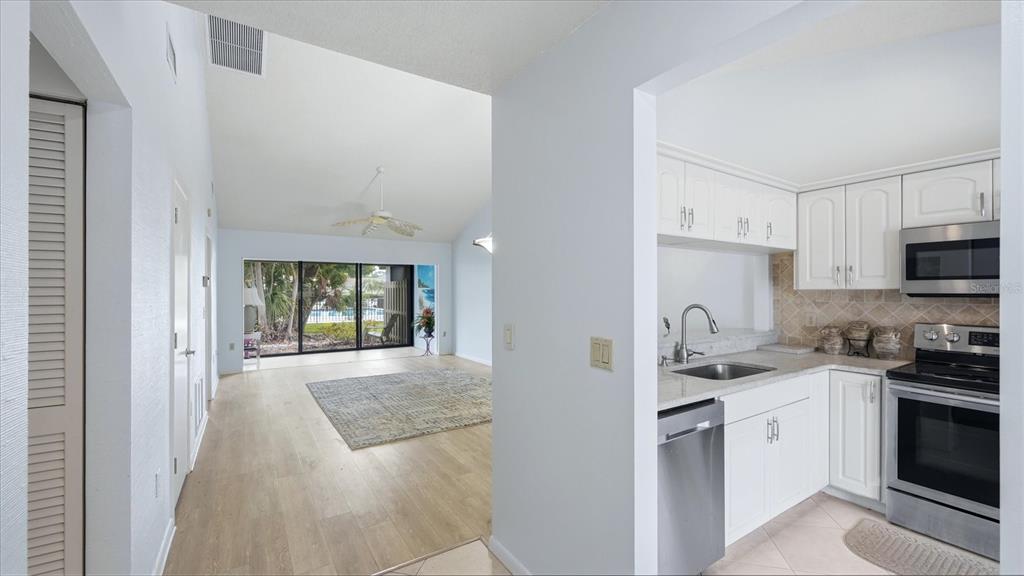 A view from a kitchen with white cabinets looking into a living room with sliding doors — 5350 MYRTLE UNIT 48, SARASOTA, FL