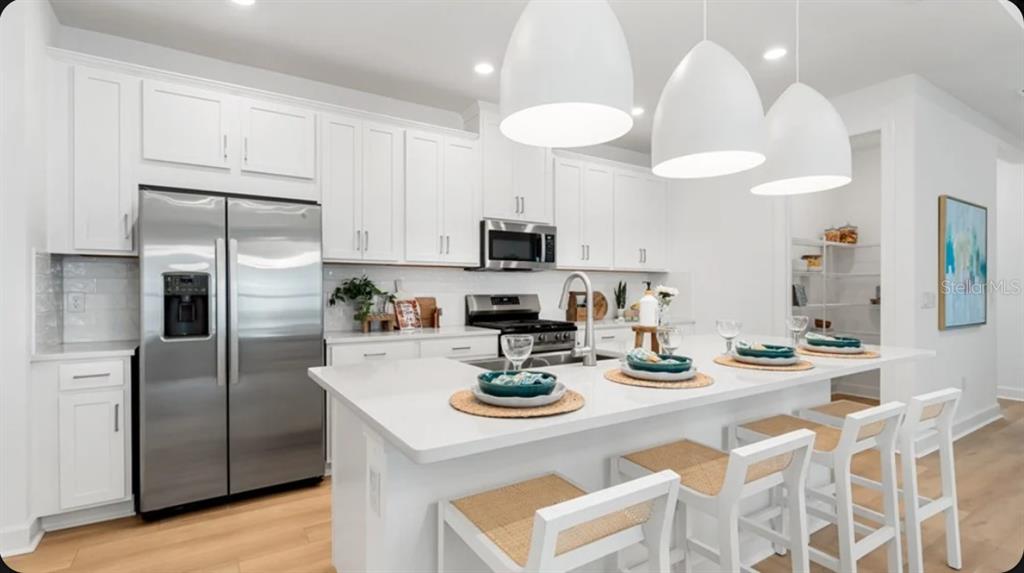 A modern kitchen features white cabinetry, stainless steel appliances, and a large central island — 13906 FLETCHER DRIVE, PALMETTO, FL