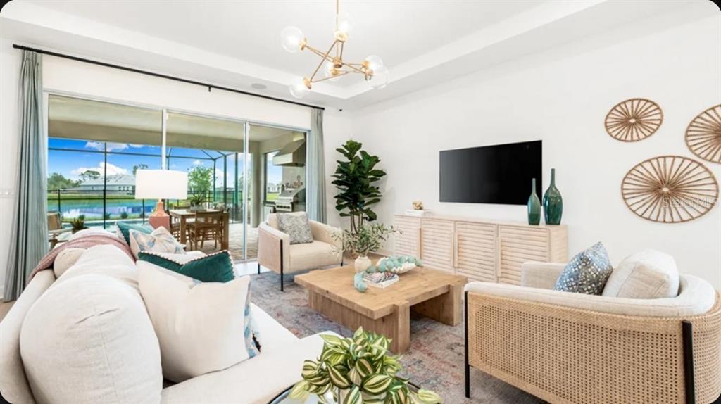 A bright living room features a light wood coffee table, neutral seating, and sliding glass doors — 13906 FLETCHER DRIVE, PALMETTO, FL