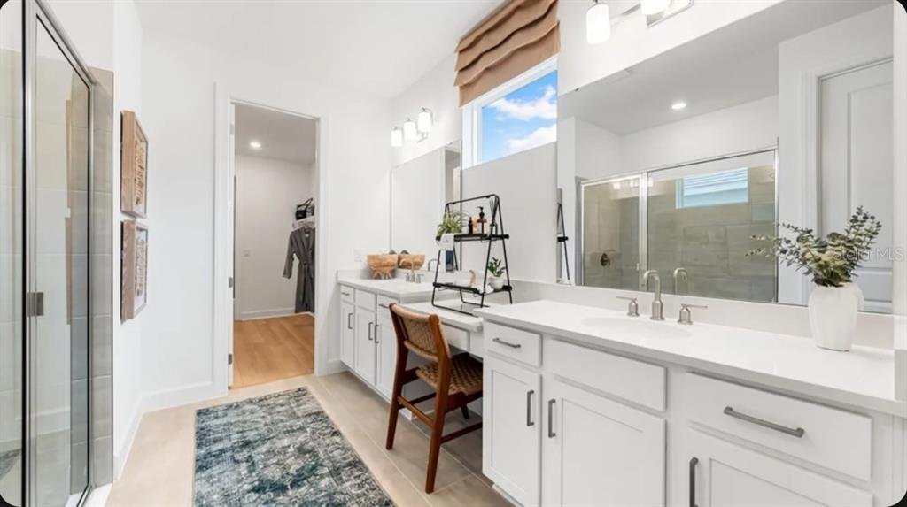 A bright bathroom features white cabinets, a makeup vanity, a large mirror, and a shower — 13906 FLETCHER DRIVE, PALMETTO, FL