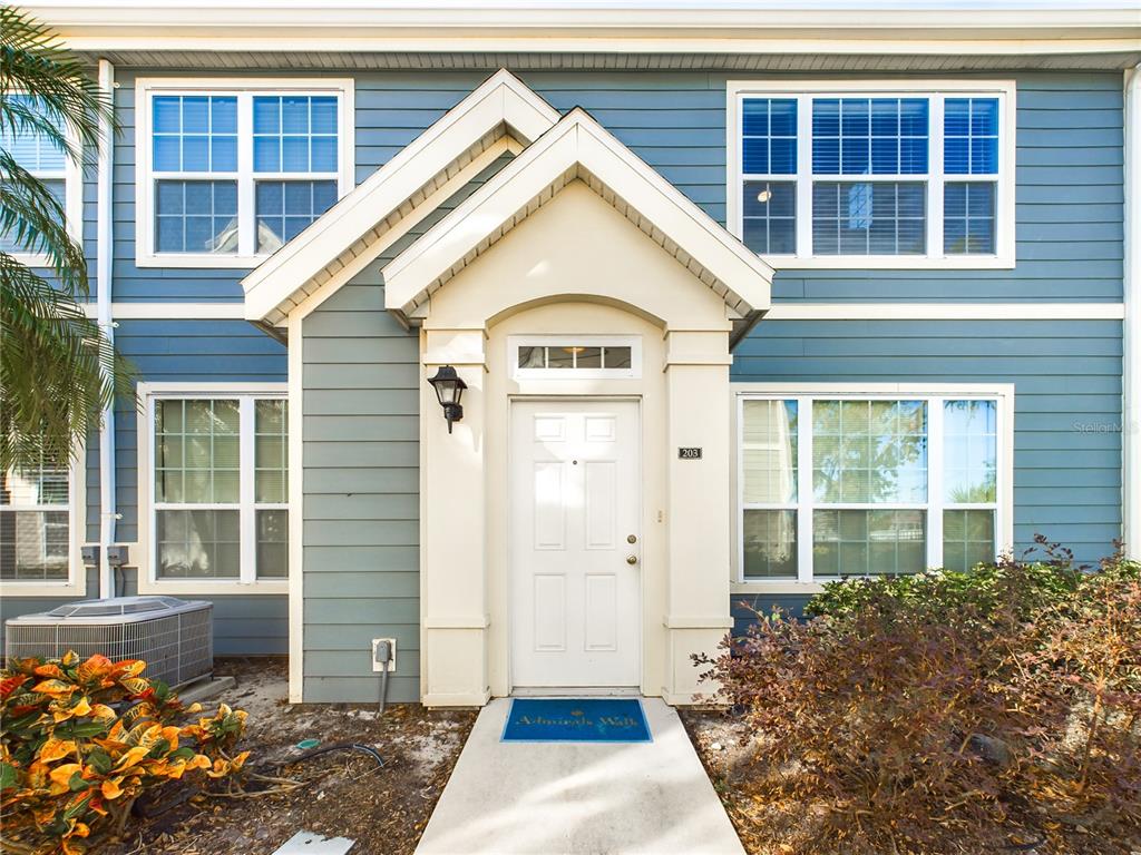 A blue-sided townhouse exterior features a white front door with a small covered entryway — 5521 ROSEHILL ROAD UNIT 203, SARASOTA, FL