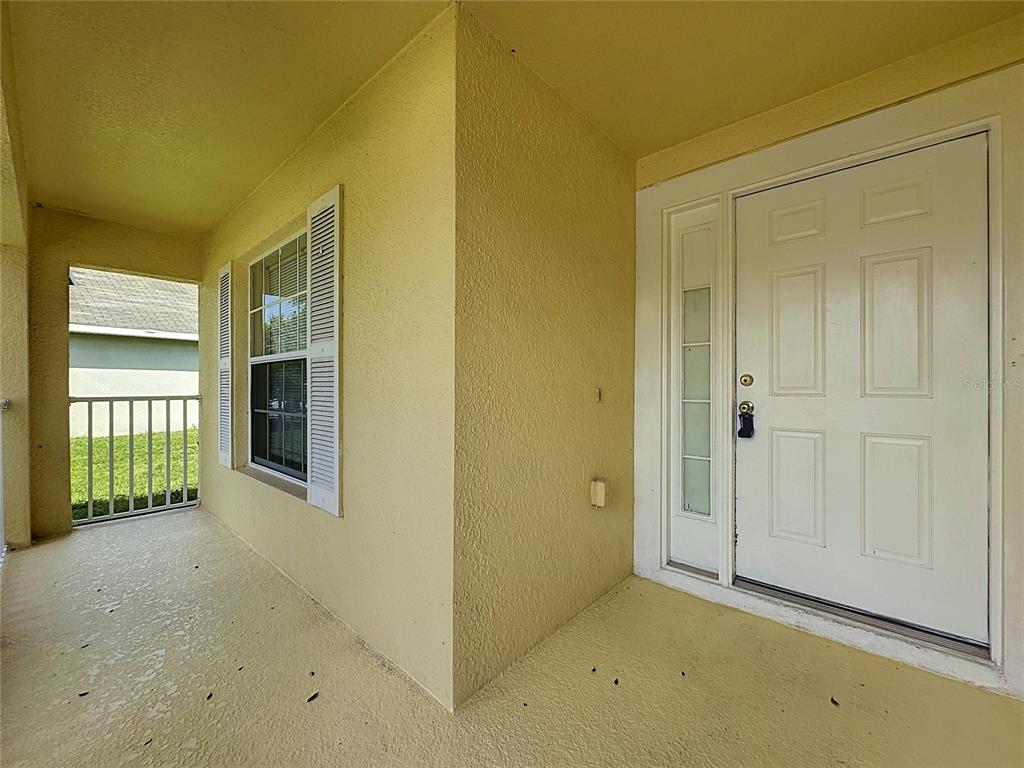 A covered entryway features a white front door with sidelights and a window with shutters — 3066 EAGLE CROSSING DR, KISSIMMEE, FL
