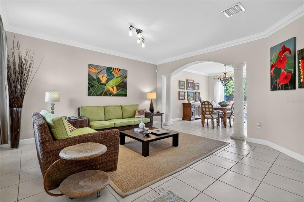 A living room with a green sofa, wicker chair, and an arched opening to a dining area — 15144 SW 20TH STREET, MIAMI, FL